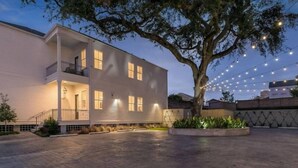 Un bâtiment à deux étages doté d’un balcon, d’une cour pavée et de guirlandes lumineuses.