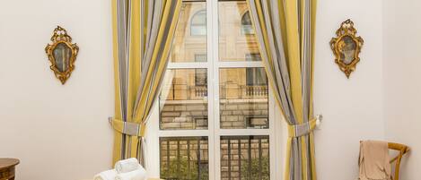 A room with a bed, a chair, and a window with curtains.