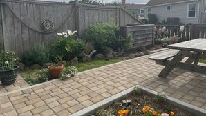 A backyard with a brick patio, a wooden fence, and various potted plants. - Enjoy Fresh Ocean Breezes, No Crowds In Small Community Setting (Bodega Bay)