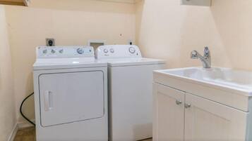 Un cuarto de lavandería con dos lavadoras blancas y un lavamanos.