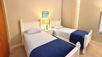 A bedroom with two single beds, a nightstand with a lamp, and a wall-mounted sign.
