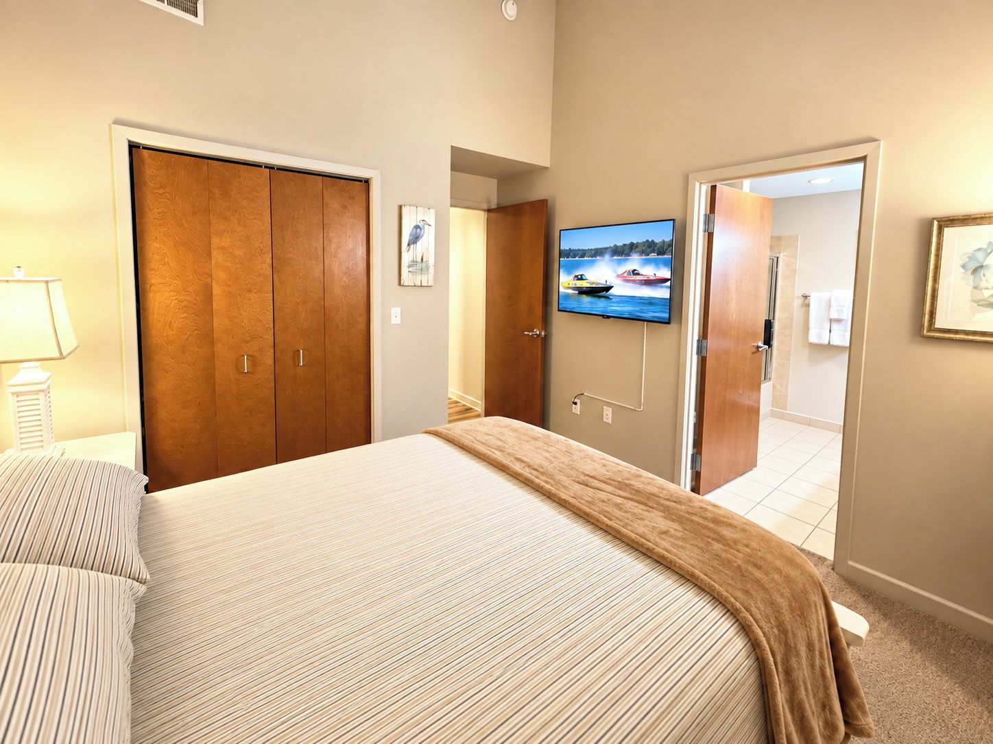 Ein Hotelzimmer mit Bett, Wandfernseher, Holzschrank und angrenzendem Badezimmer.