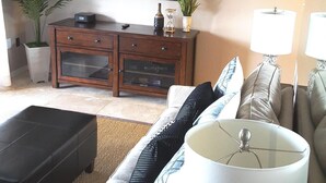 Een woonkamer met een bank, een salontafel, een televisie, een kast en twee lampen.