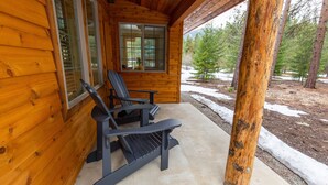 Puuinen mökki, jonka edessä on kaksi Adirondack-tyylistä puutarhatuolia, ikkunassa on sälekaihtimet ja ikkunasta avautuu lumisen maiseman näkymä, jossa on myös puita.