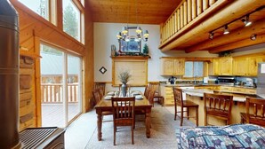 L’intérieur chaleureux d’un chalet comprend un coin repas, une cuisine et une grande fenêtre donnant sur une terrasse.