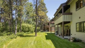 Une maison à deux étages avec une pelouse bien entretenue et une zone boisée.