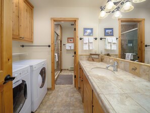 Une petite salle de bain comprenant un lave-linge, un lavabo et un espace douche.