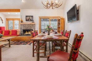 Un coin repas avec une cheminée, des chaises en bois et une table dressée pour quatre personnes.