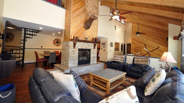 A spacious living area with a fireplace, leather sofas, and a dining area with a red curtain. - Eagle's Ridge Lodge- 7 MIN WALK TO PEAK 9 & DOWNTOWN (Breckenridge)