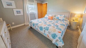 A bedroom with a bed, a dresser, a lamp, and a picture on the wall. - Hatteras Island Charmer! (Salvo)