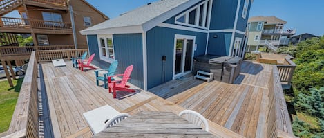 A wooden deck with a table and chairs, a small blue building with a door, and a wooden staircase.