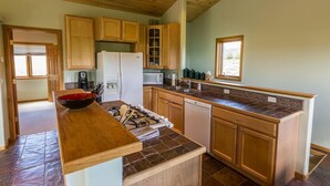 A kitchen with wooden cabinets, a central island with a red bowl, a stove, and a refrigerator. - Family Friendly - On Ten Acres 3 Miles to Town - Stunning Views and Country Feel (Crested Butte)