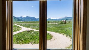 A window with a view of a rural landscape, including a dirt road and houses. - Family Friendly - On Ten Acres 3 Miles to Town - Stunning Views and Country Feel (Crested Butte)