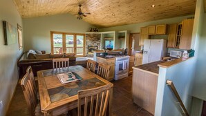 A spacious kitchen with wooden cabinets, a dining area with a table and chairs, and a stone fireplace. - Family Friendly - On Ten Acres 3 Miles to Town - Stunning Views and Country Feel (Crested Butte)