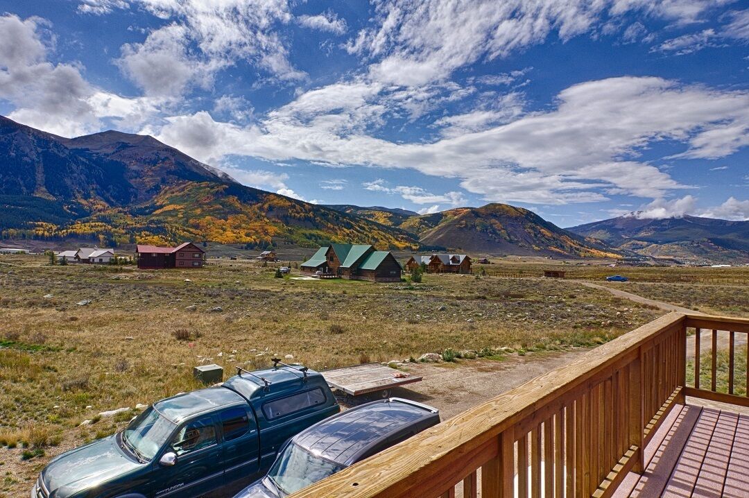 A scenic view of a mountainous area with cabins and a wooden deck overlooking a parking area.