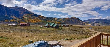 A scenic view of a mountainous area with cabins and a wooden deck overlooking a parking area.