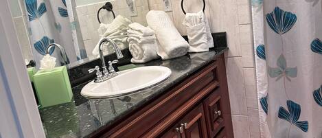 A bathroom with a white sink, dark wooden vanity, and a mirror.