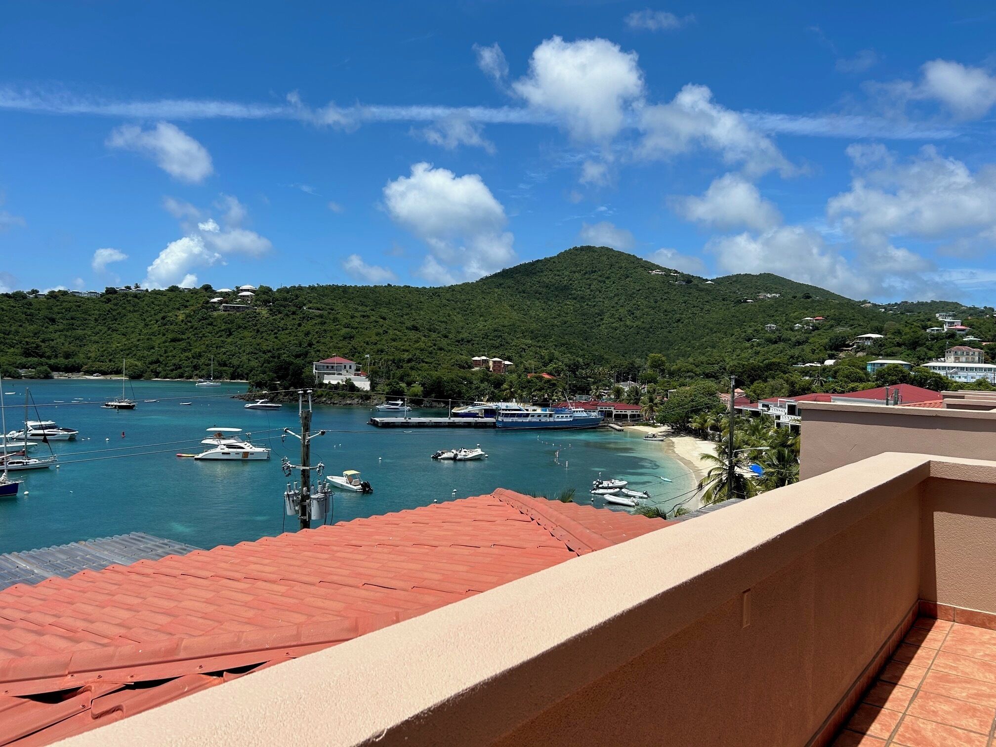 A coastal view with boats, a beach, and a mountain.