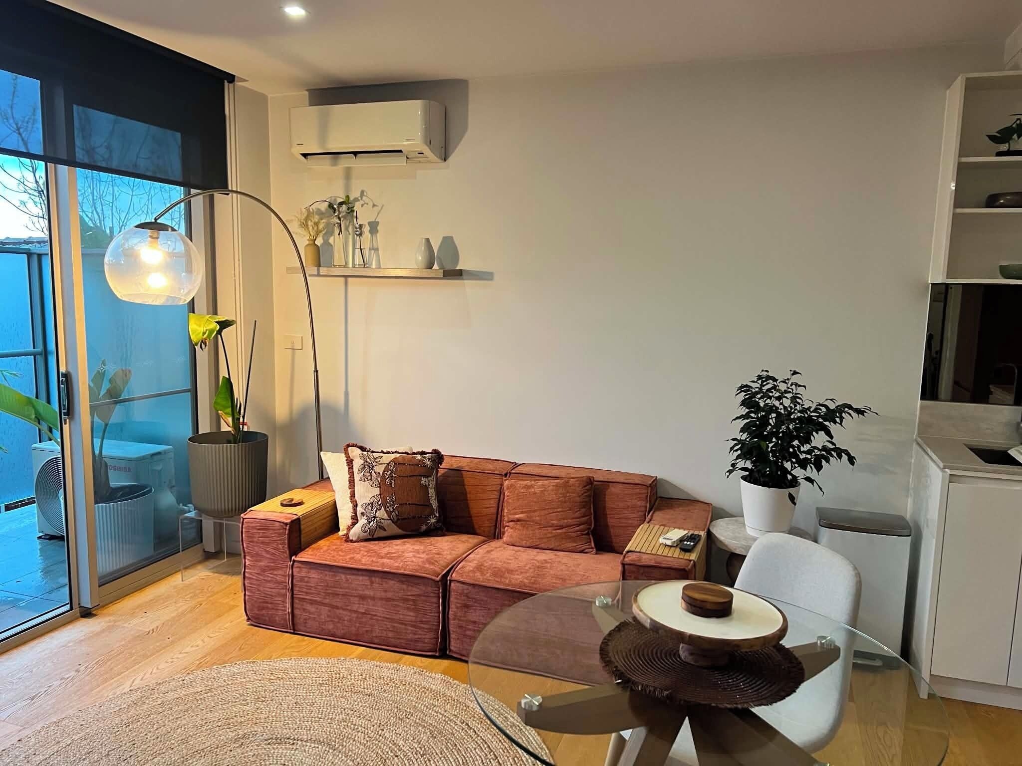 Una sala moderna con un sofá, una mesa de centro de cristal y una planta en maceta.
