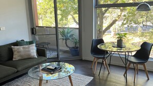 A modern living room with a glass coffee table, a sofa, and two chairs. - Centrepoint Units Heidelberg (Heidelberg)
