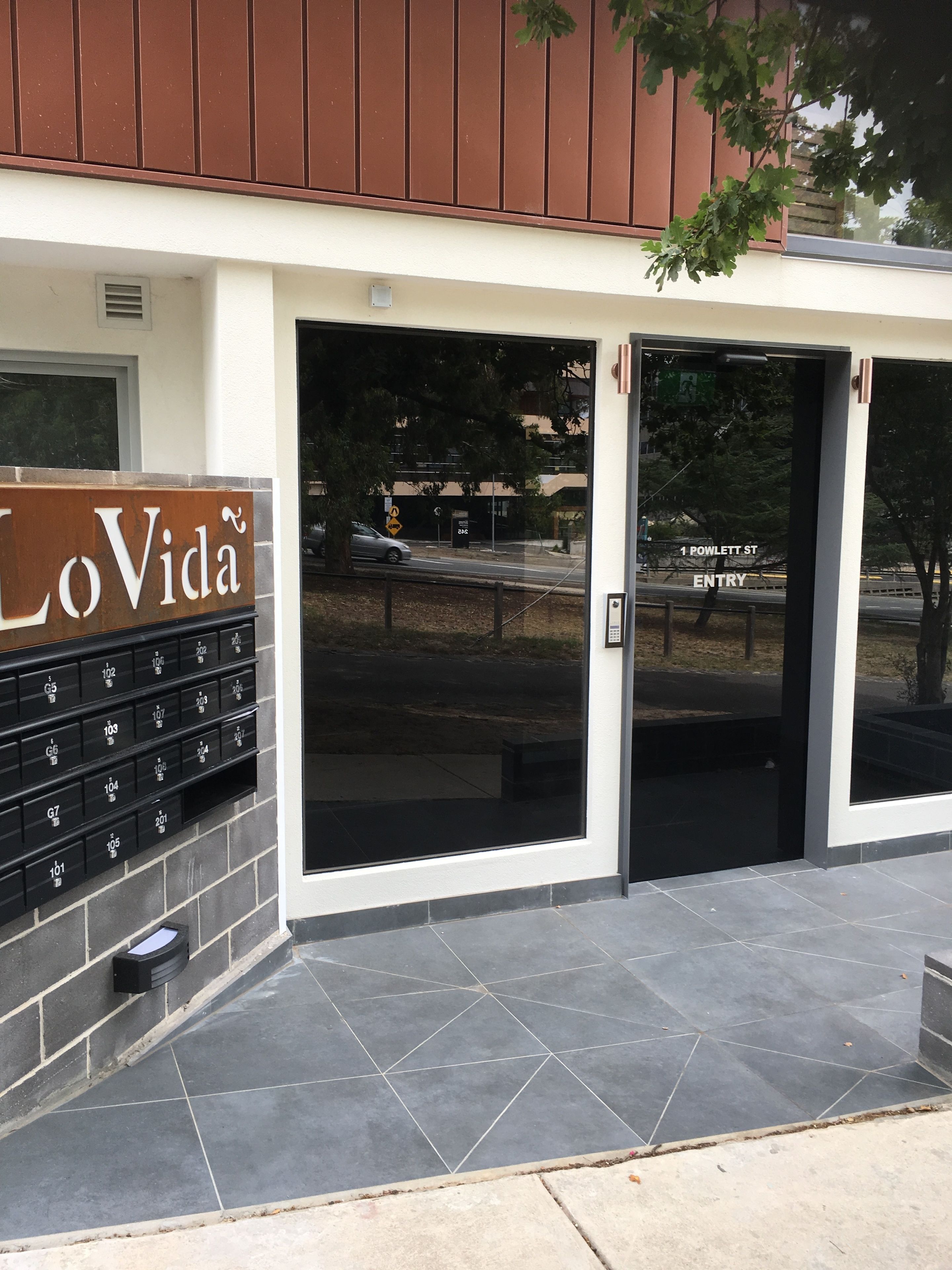 La entrada de un edificio con un letrero que dice "LoVida" y un área de buzones.