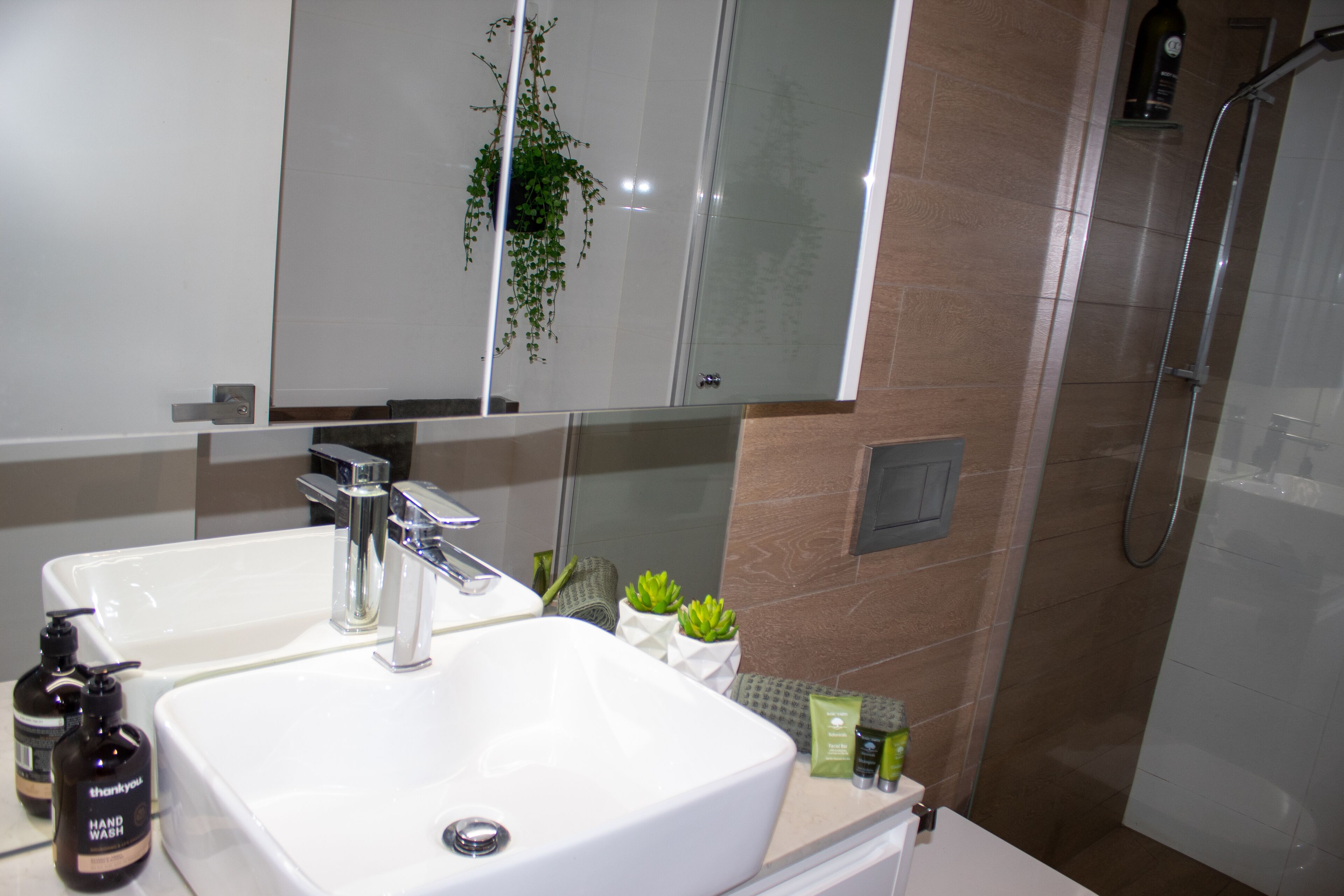 Ein modernes Badezimmer mit zwei Waschbecken, einem Spiegel und einer Dusche.