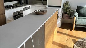 A modern kitchen with white cabinets, a central island, and a built-in oven. - Centrepoint Units Heidelberg (Heidelberg)