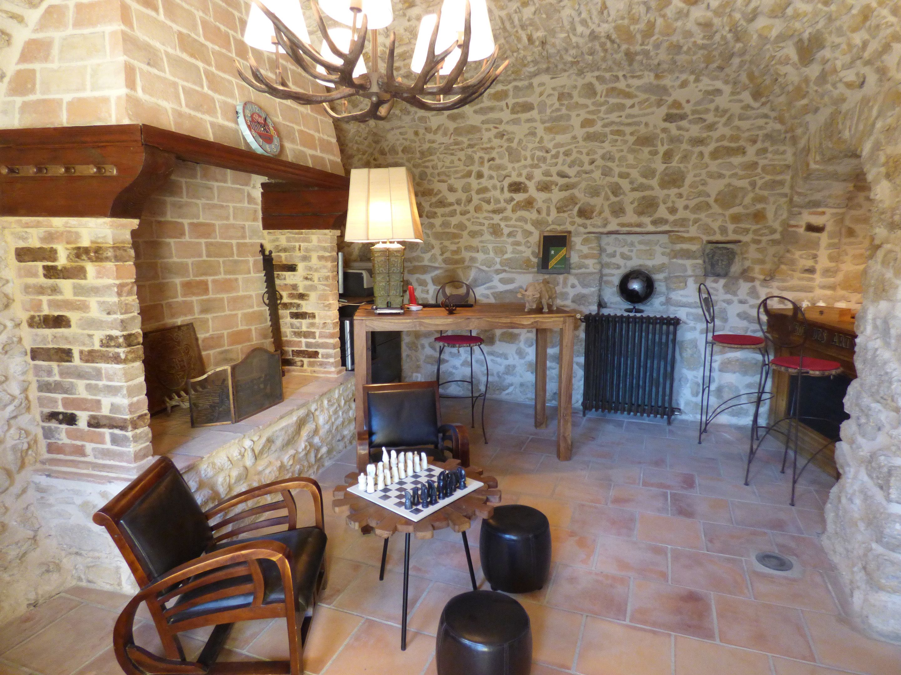 A cozy room with a fireplace, a table with a chessboard, and two chairs.