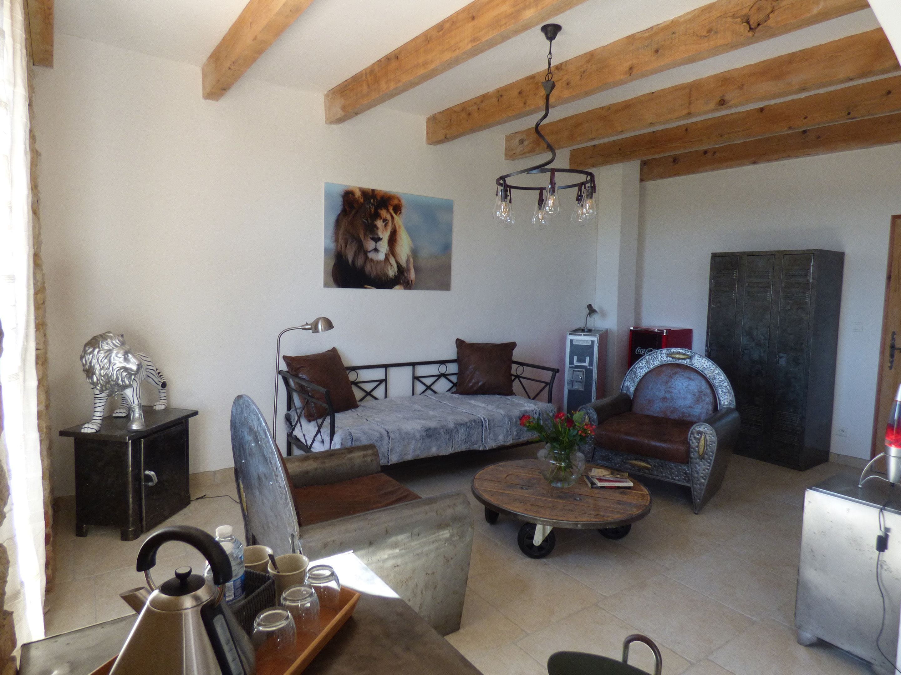 A living room with a sofa, a coffee table, a chandelier, and a painting of a lion.