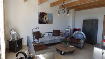 A living room with a sofa, a coffee table, a chandelier, and a painting of a lion.