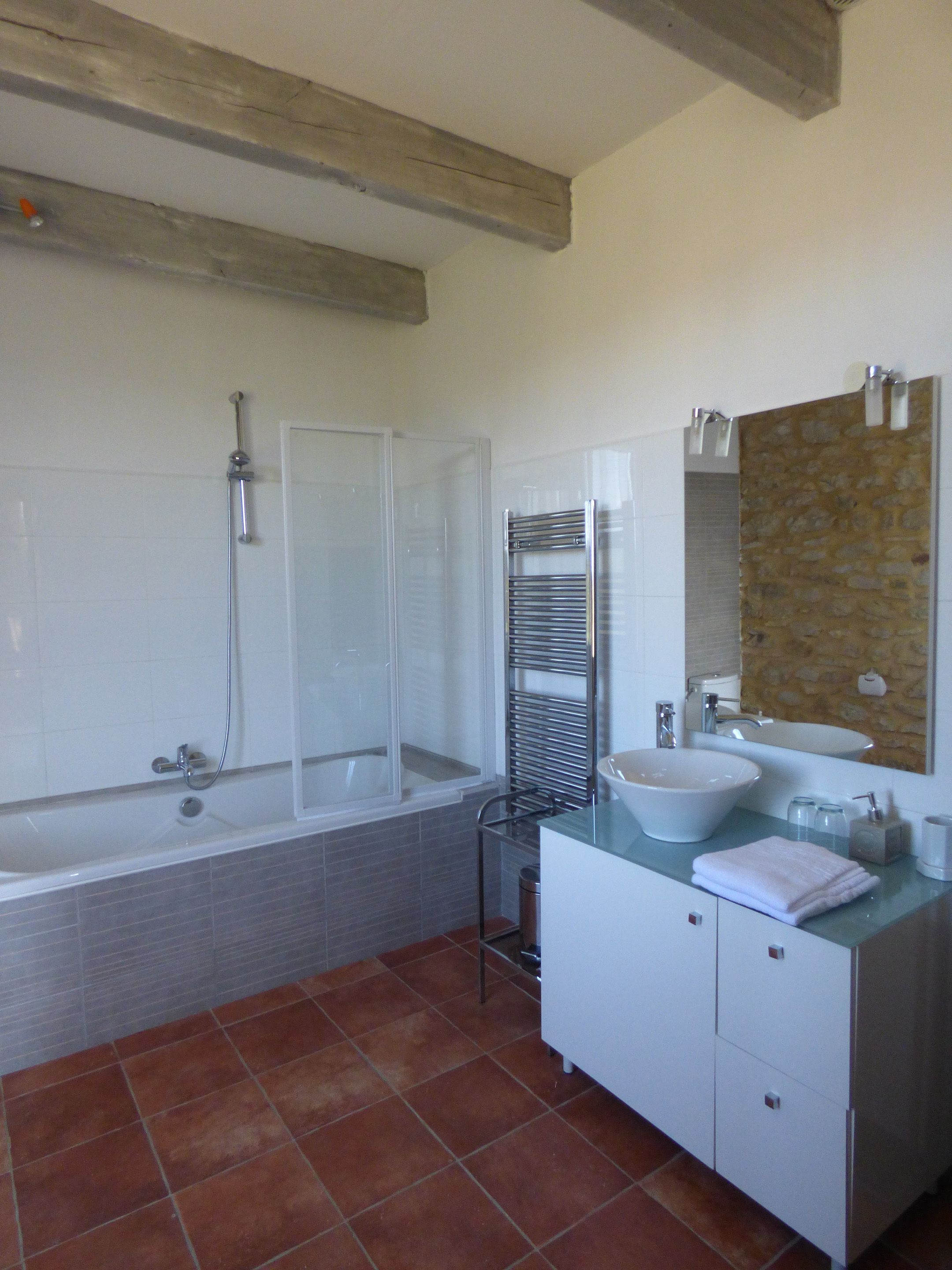 A bathroom with a bathtub, shower, vanity with a sink, and a towel rack.