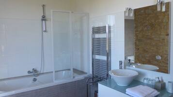 A bathroom with a bathtub, shower, vanity with a sink, and a towel rack.