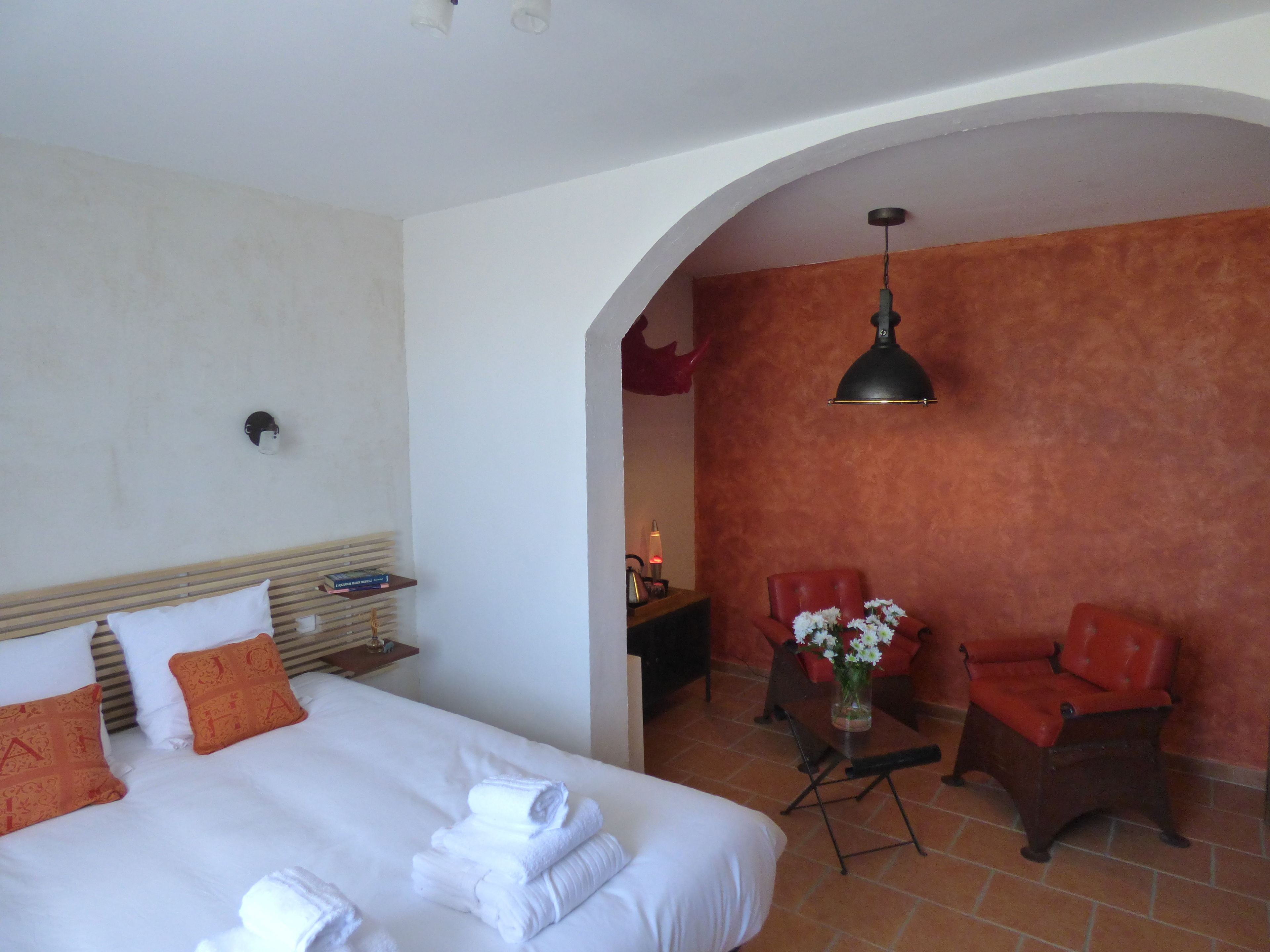 Una habitación de hotel con una cama, un escritorio, una silla y una mesa con un florero.