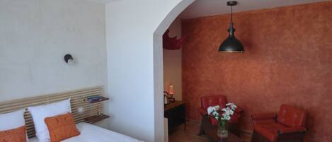 Una habitación de hotel con una cama, un escritorio, una silla y una mesa con un florero.