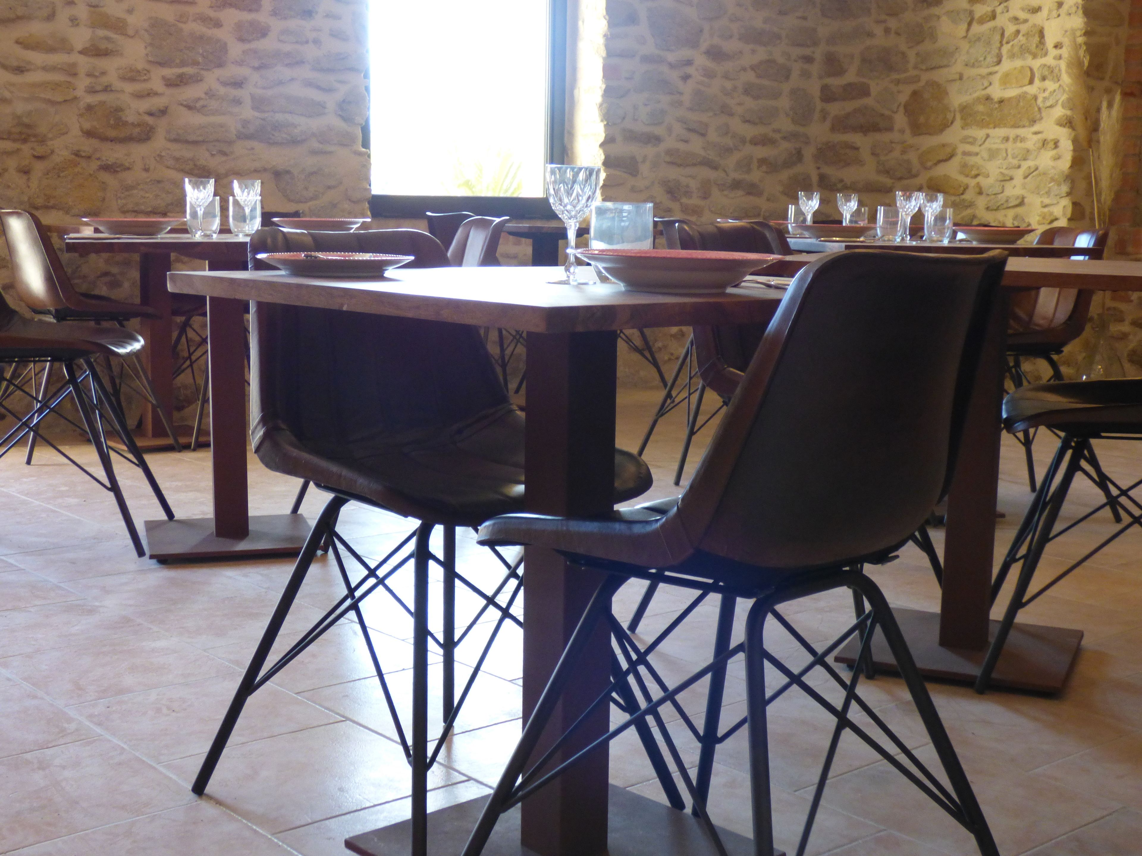 A restaurant with stone walls and tiled flooring, featuring tables set with plates, glasses, and cutlery.