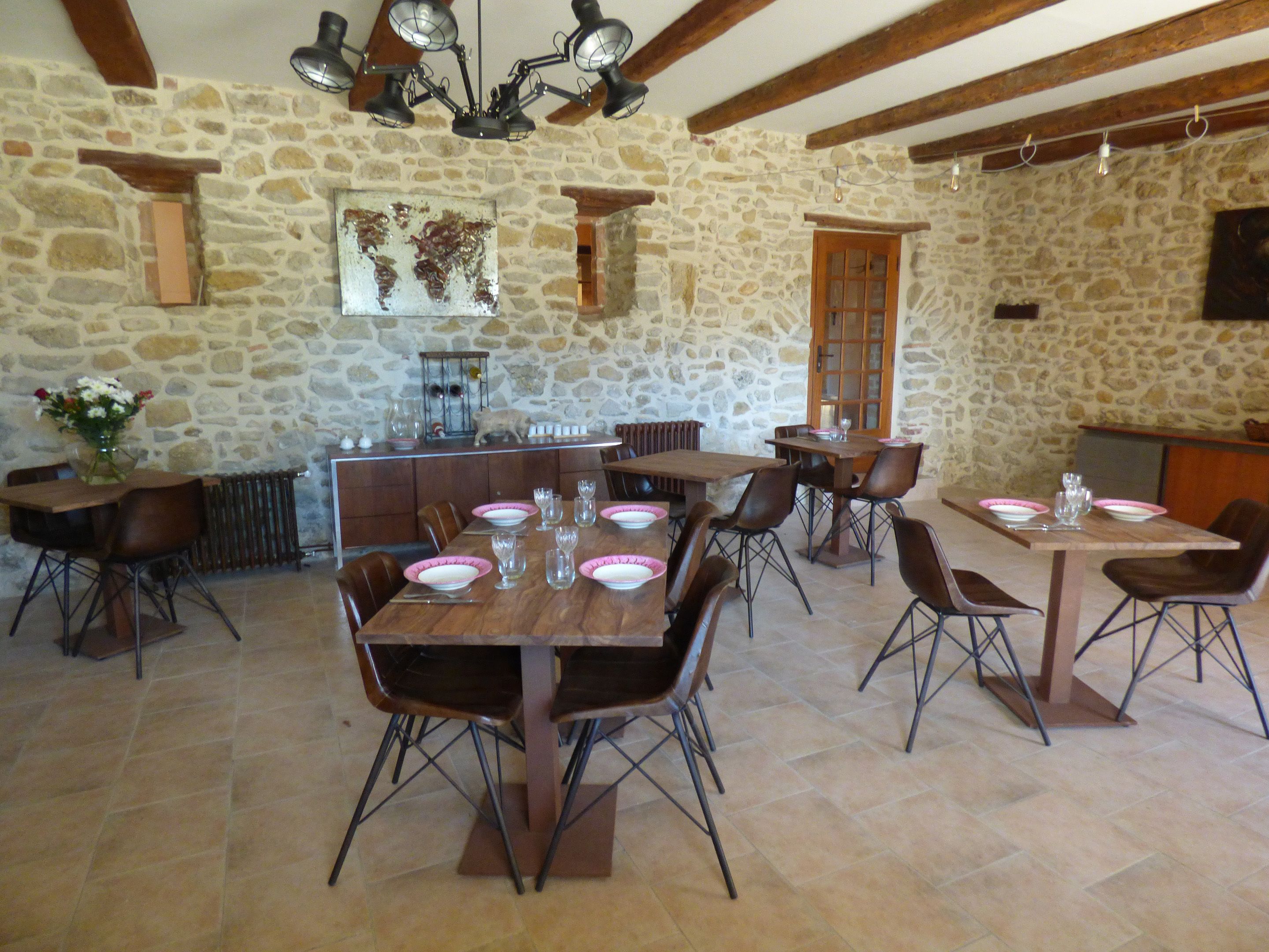 Comedor de paredes de piedra con mesas y sillas de madera, un mapa mundial en la pared y una chimenea de piedra.