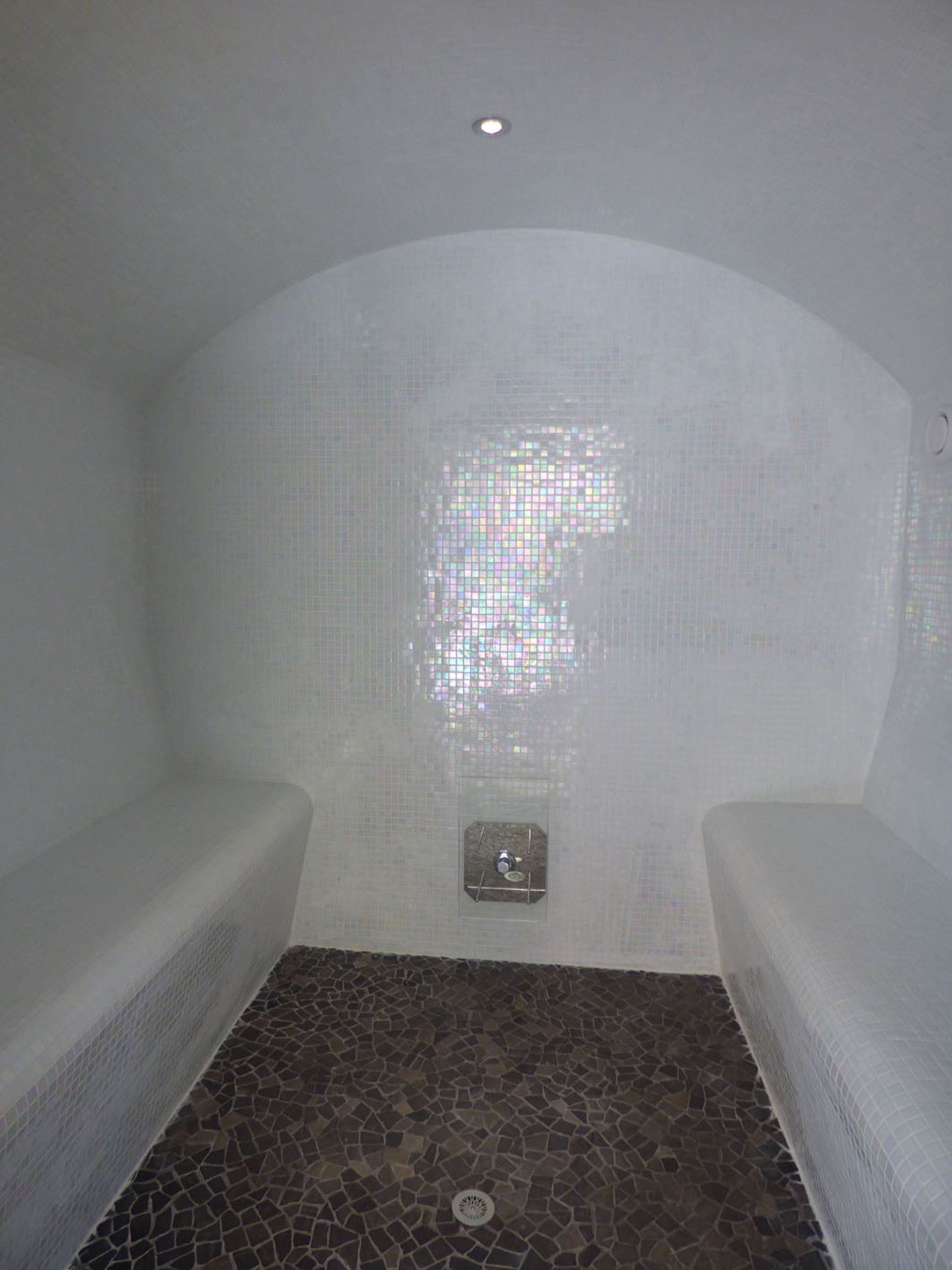 Un cuarto de spa con dos bancos, suelo de baldosas y una lámpara en el techo.