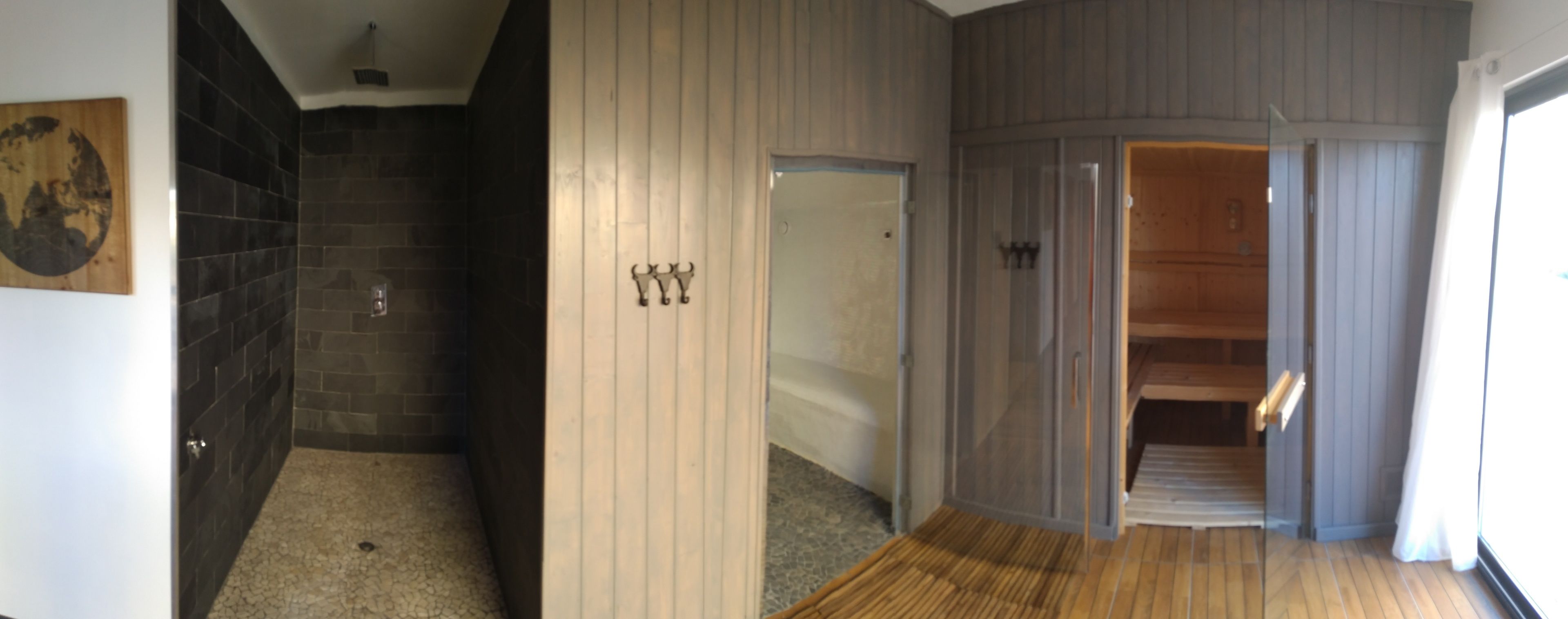 Un pasillo con una zona de ducha enlosetada, una puerta de madera y un piso de madera.