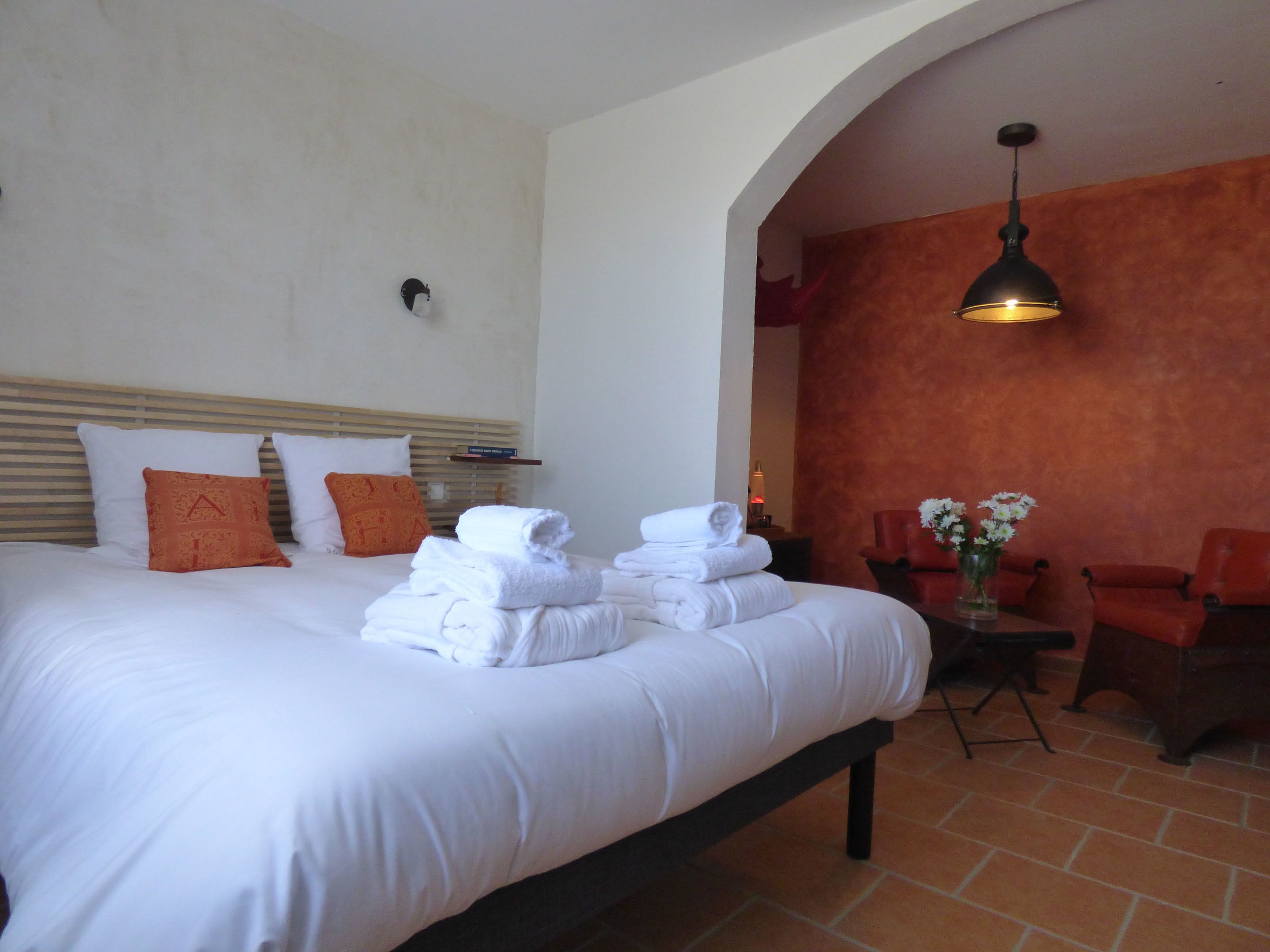 Habitación de hotel con una cama grande, una mesita con un florero y una zona de estar con sillas.