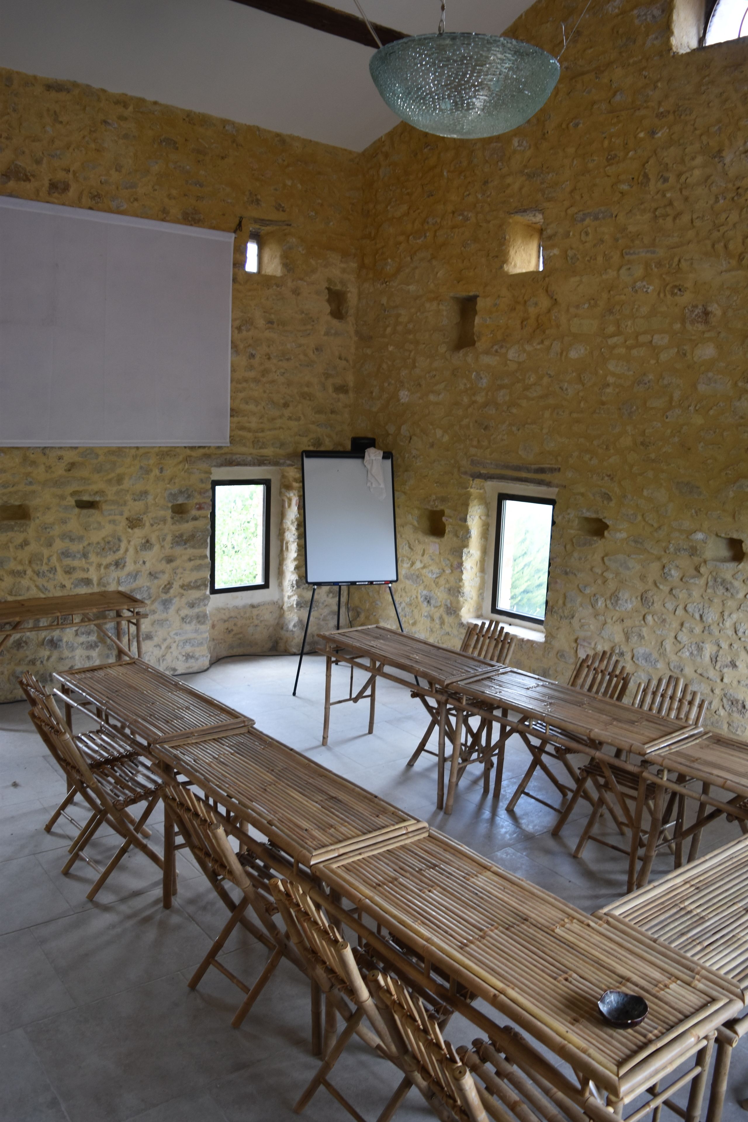 A conference room with a large table, chairs, a whiteboard, and a projector screen.