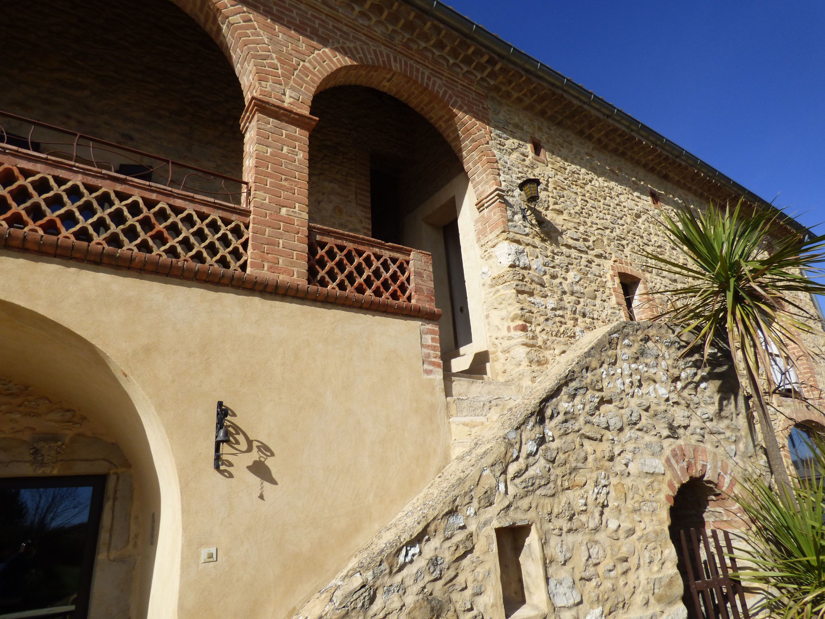 A building with a stone facade, arched windows, and a balcony with a lattice design.