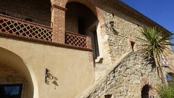 A building with a stone facade, arched windows, and a balcony with a lattice design.
