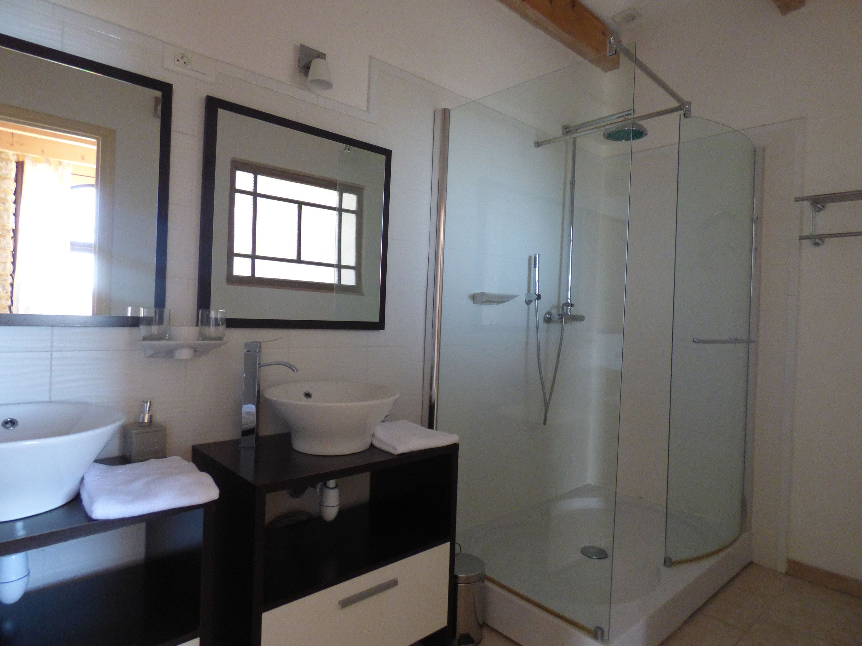 A bathroom with a glass-enclosed shower, a white sink, and a mirror above the sink.
