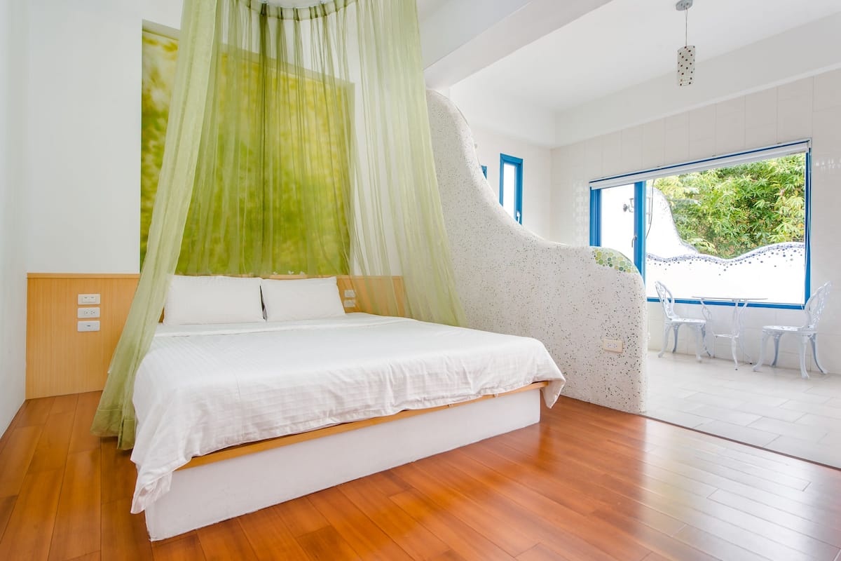 A bedroom with a bed, a canopy, a view of the outdoors, and a seating area with chairs.