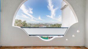 A room with a white wall and a large arched window overlooking a cityscape. - White Lighthouse B&B (Liuqiu)