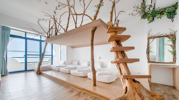 A modern room with a wooden staircase, white sofas, and a large window. - White Lighthouse B&B (Liuqiu)