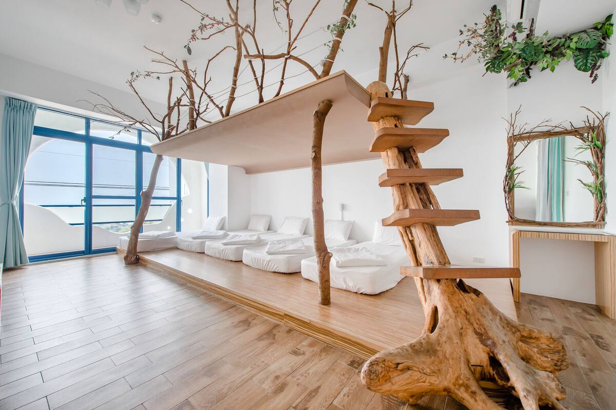A modern room with a wooden staircase, white sofas, and a large window.
