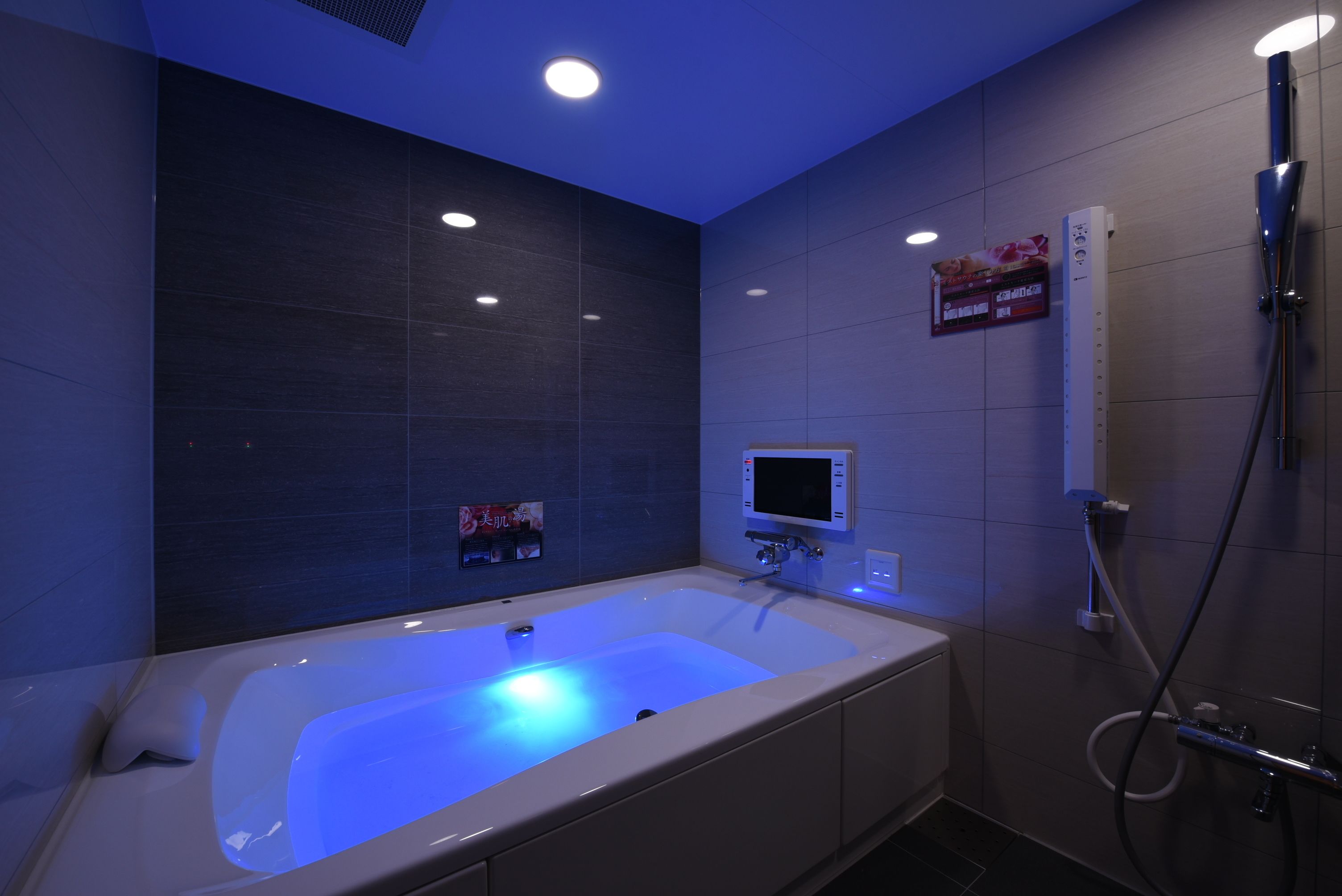 A modern bathroom with a large bathtub, a shower area, and a digital control panel.
