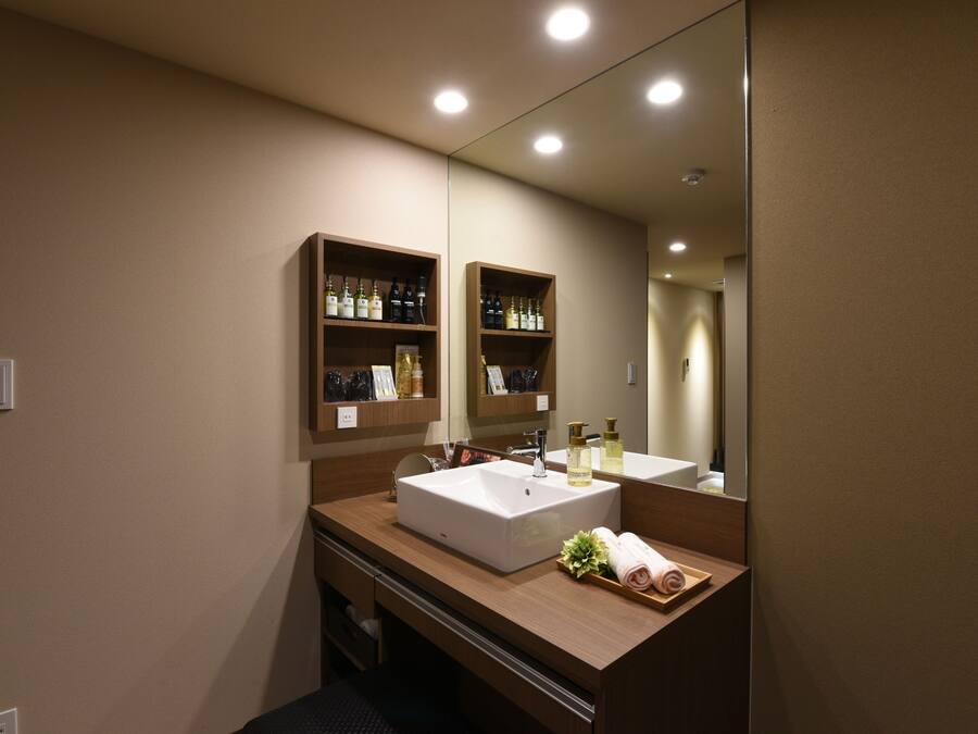 A modern bathroom with a large mirror, two sinks, wooden shelves with toiletries, and a towel rack.