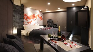 A modern hotel room with a bed, a dining table with a bottle and glasses, a chair, and a television. - Restay Onoji - Adults Only (Machida)